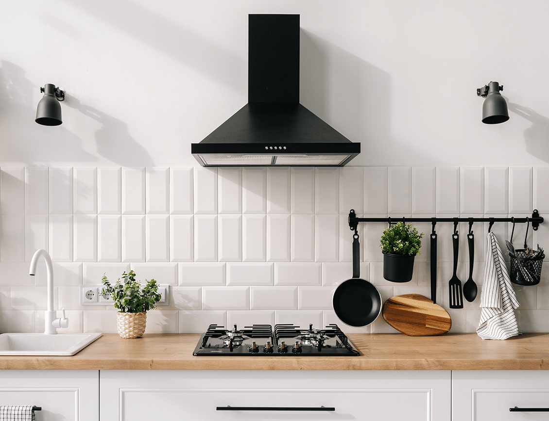thermador-internal-1 a bright white kitchen with a black vent hood and built-in cooktop